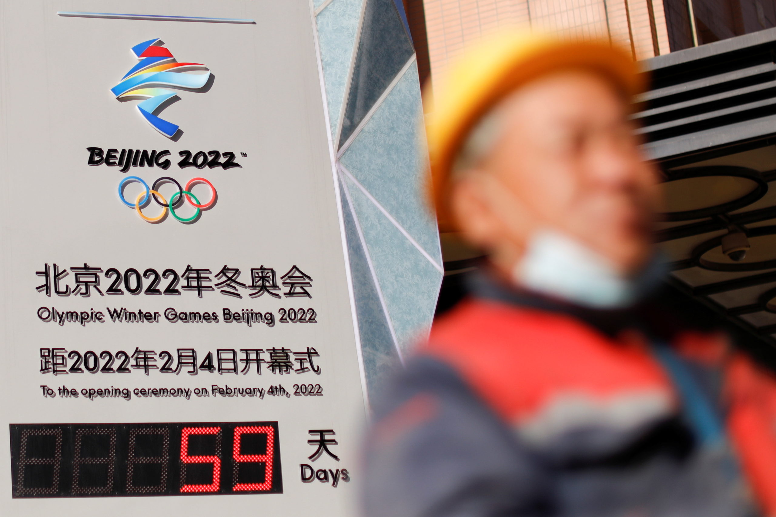 A worker walks past a countdown clock for the Beijing 2022 Winter Olympic Games in Beijing, China December 7, 2021.
