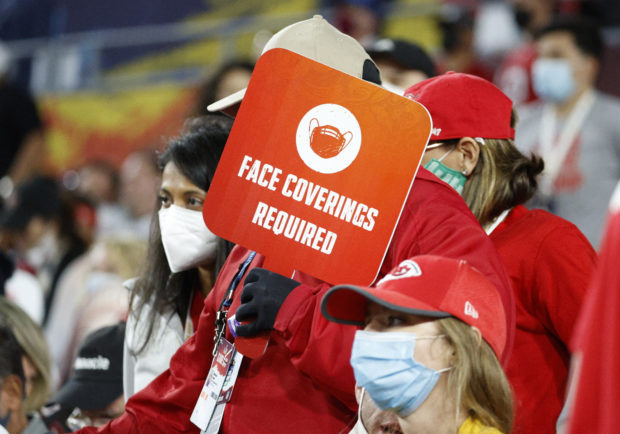 Super Bowl LV - Tampa Bay Buccaneers v Kansas City Chiefs - Raymond James Stadium, Tampa, Florida, U.S. - February 7, 2021 A member of staff displaying a banner to wear a protective face mask due to the coronavirus disease (COVID-19)  REUTERS/Eve Edelheit
