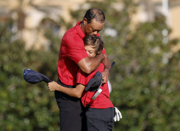 Golf - PNC Championship - The Ritz-Carlton Golf Club, Orlando, Florida, U.S. - December 19, 2021 Tiger Woods of the U.S. embraces his son Charlie on the 18th green during the second round REUTERS/Joe Skipper