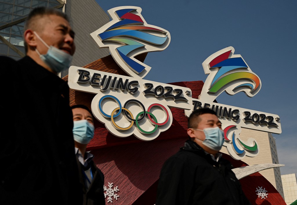People walk past the logos of the Beijing 2022 Winter Olympics and Paralympic Winter Games in Beijing on January 18, 2022.