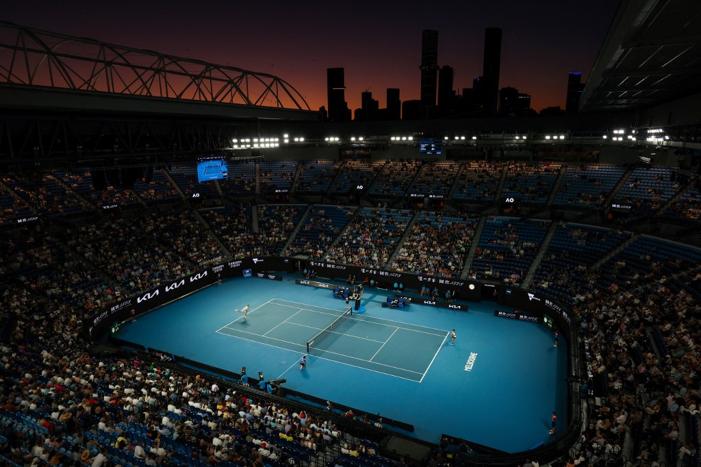 The sun sets as Germany's Alexander Zverev (L) serves against Australia's John Millman during their men's singles match on day three of the Australian Open tennis tournament in Melbourne on January 19, 2022.