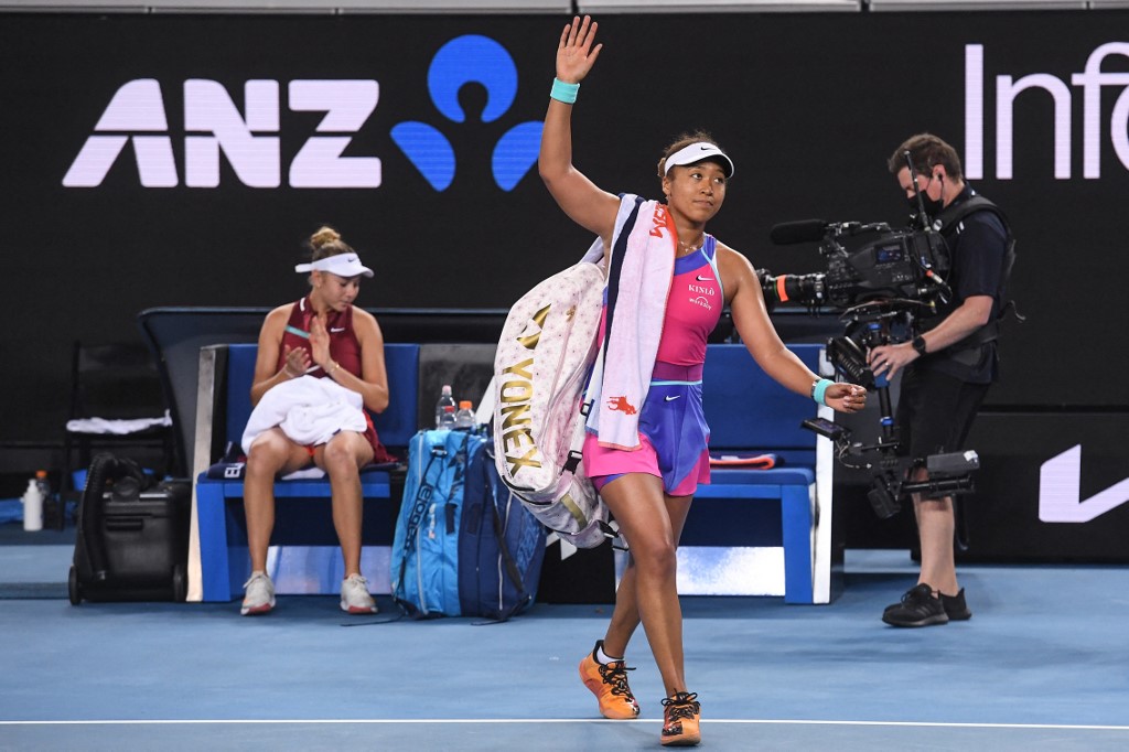 Japan's Naomi Osaka waves as she walks off the court after losing to Amanda Anisimova of the US (L) in their women's singles match on day five of the Australian Open tennis tournament in Melbourne on January 21, 2022.