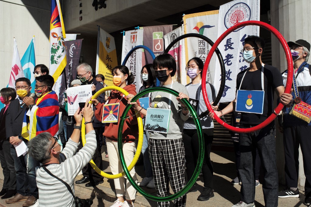 Activists hold up banners and the five Olympic Rings to protest against the 2022 Beijing Olympic Games, which begin on February 4, outside the Parliament in Taipei on January 26, 2022.