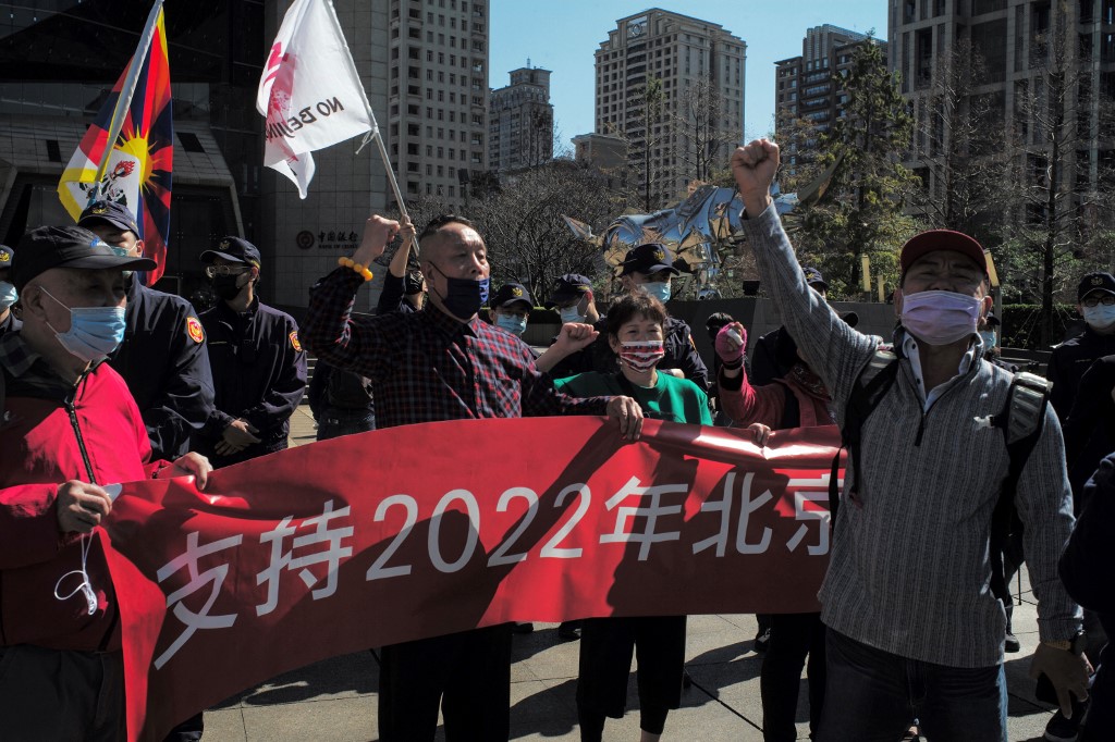 Police (C-in background) stand between a group of supporters (foreground) of the 2022 Beijing Olympic Games shouting to counter against another group of anti-Olympic protesters (back R) holding flags, outside the Bank of China in Taipei on January 26, 2022. 