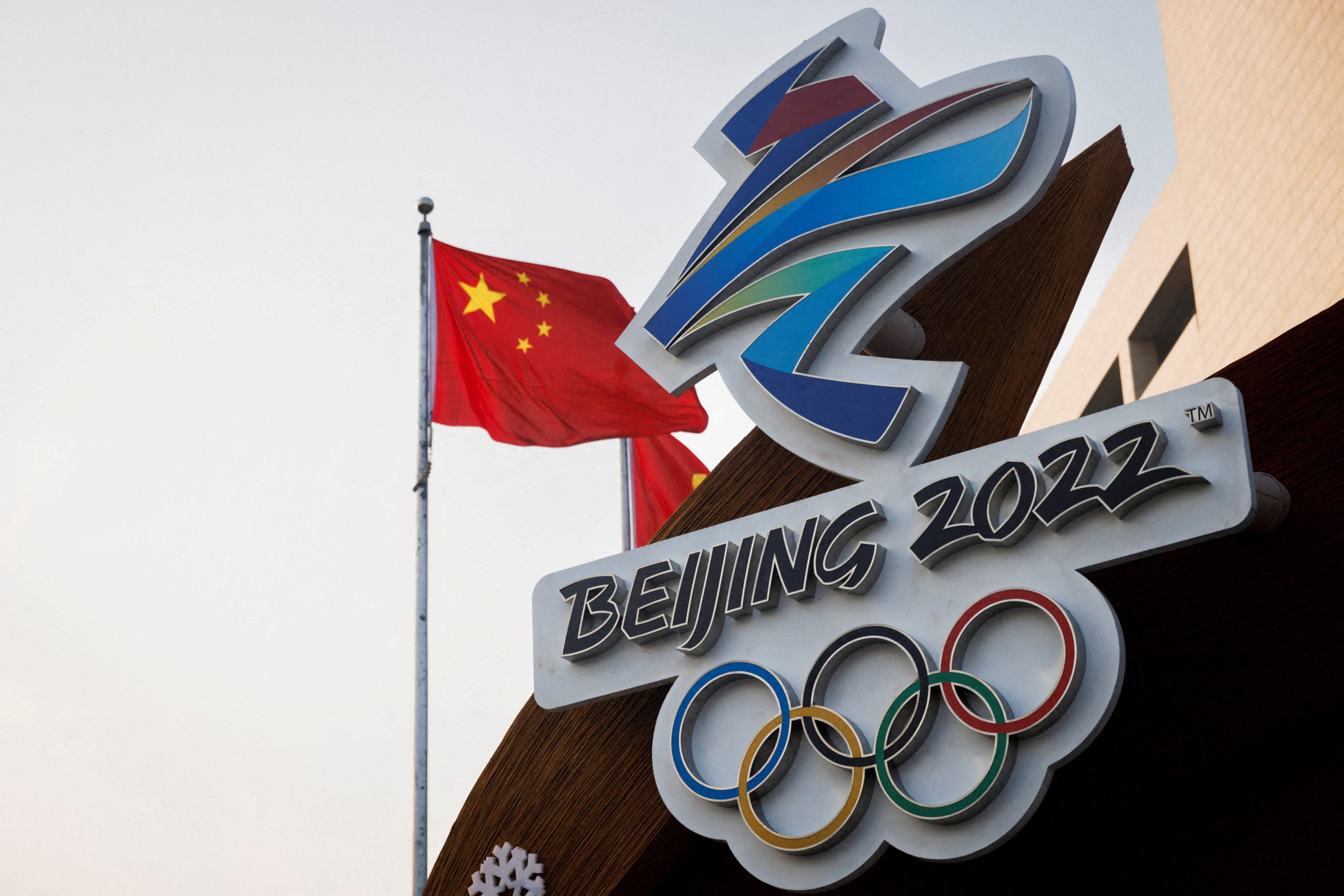 FILE PHOTO: The Chinese national flag flies behind the logo of the Beijing 2022 Winter Olympics in Beijing, China, January 14, 2022. REUTERS/Thomas Peter/File Photo