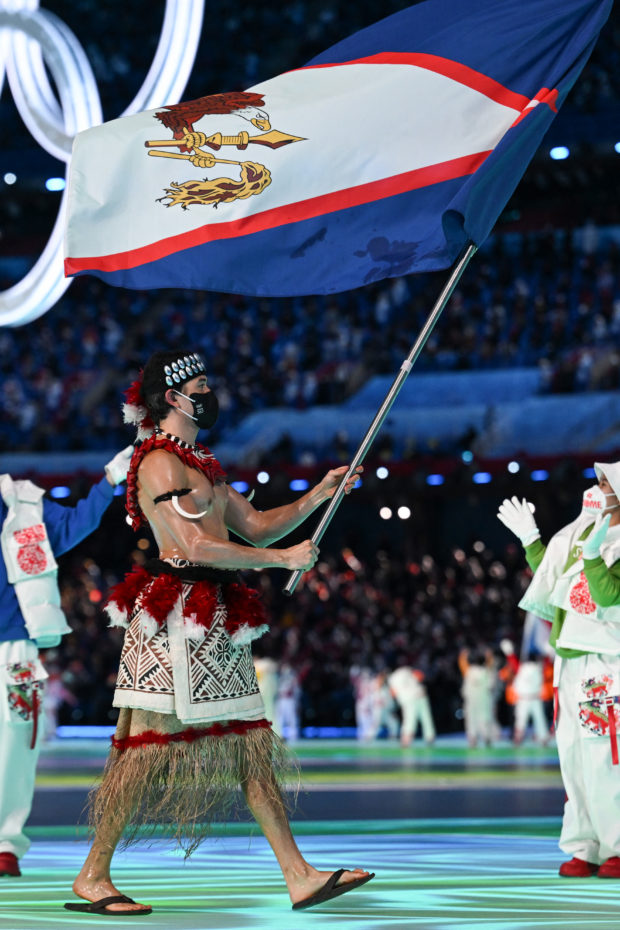 American Samoa's flag bearer Nathan Crumpton takes part in the parade of athletes during the opening ceremony of the Beijing 2022 Winter Olympic Games, at the National Stadium, known as the Bird's Nest, in Beijing, on February 4, 2022. (Photo by Lillian SUWANRUMPHA / AFP)