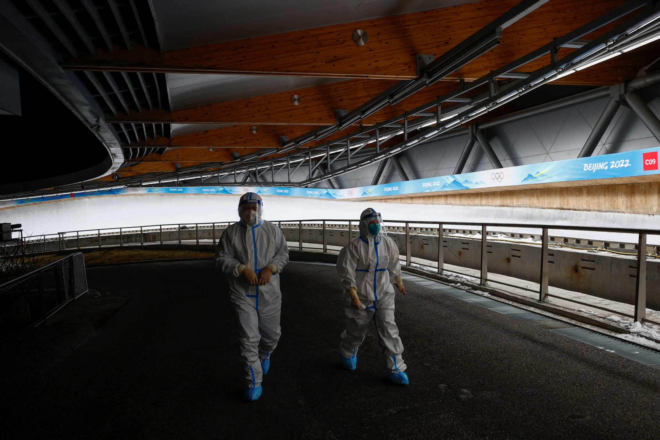 Staff wearing full body suits as protection against the coronavirus disease (COVID-19) walk along the track of the National Sliding Centre at the Beijing 2022 Winter Olympics, in Beijing, China, February 1, 2022. Picture taken February 1, 2022.