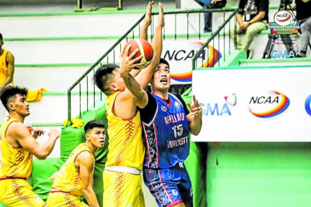 Justin Araña scores on a reverse layup despite heavy pressure. He was wheeled off the court late in the contest. —CONTRIBUTED PHOTO