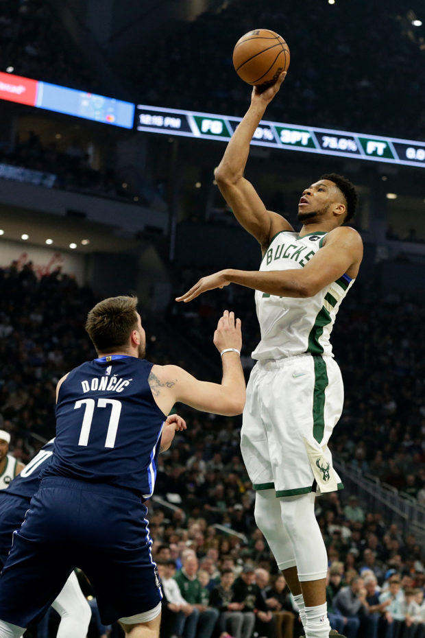 Giannis Antetokounmpo #34 of the Milwaukee Bucks scores over Luka Doncic #77 of the Dallas Mavericks during the first half of a game at Fiserv Forum on April 03, 2022 in Milwaukee, Wisconsin. NOTE TO USER: User expressly acknowledges and agrees that, by downloading and or using this photograph, User is consenting to the terms and conditions of the Getty Images License Agreement.   John Fisher/Getty Images/AFP (Photo by John Fisher / GETTY IMAGES NORTH AMERICA / Getty Images via AFP)