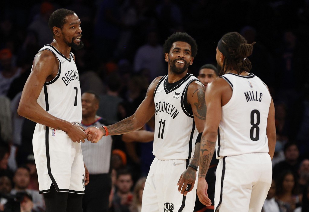 Patty Mills #8, Kevin Durant #7, and Kyrie Irving #11 of the Brooklyn Nets react during the second half against the New York Knicks at Madison Square Garden on April 06, 2022 in New York City. The Nets won 110-98. 