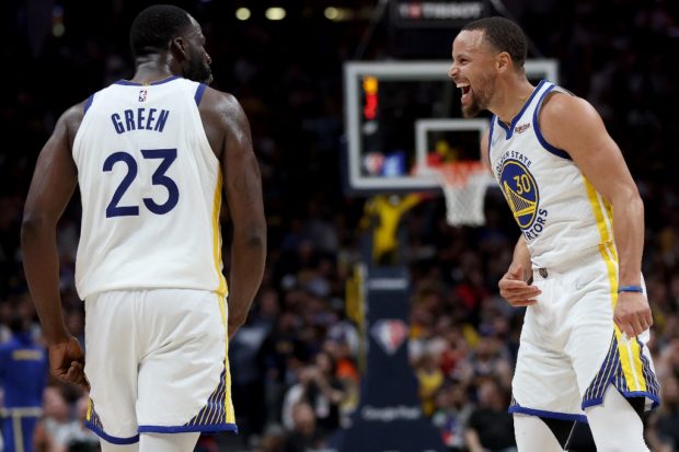 Draymond Green #23 and Stephen Curry #30 of the Golden State Warriors celebrate against the Denver Nuggets in the fourth quarter during Game Three of the Western Conference First Round NBA Playoffs at Ball Arena on April 21, 2022 in Denver, Colorado.
