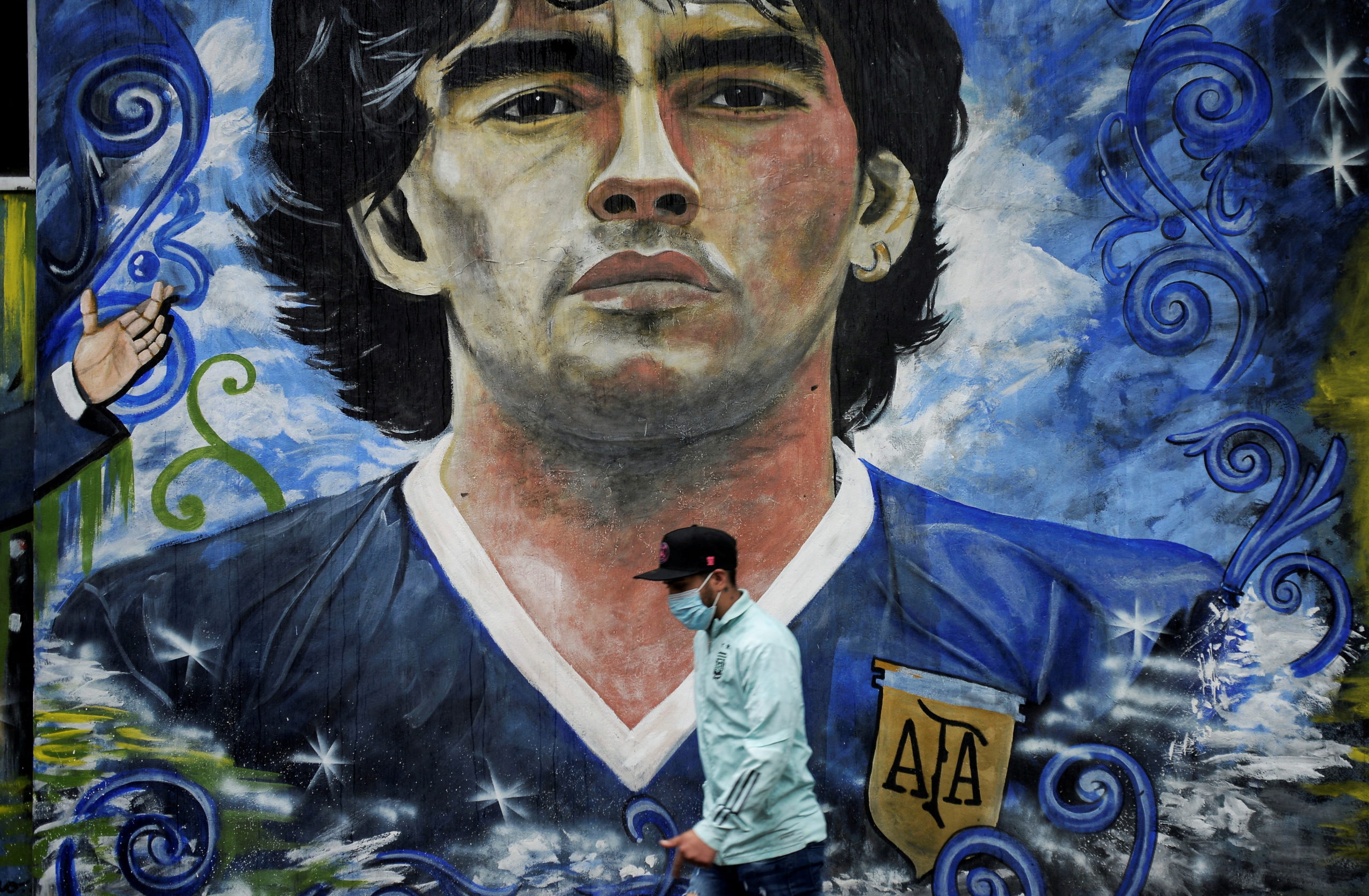 FILE PHOTO: A pedestrian walks past a mural depicting the late football legend Diego Armando Maradona in La Boca, on the anniversary of his first death, Buenos Aires, Argentina November 25, 2021. 