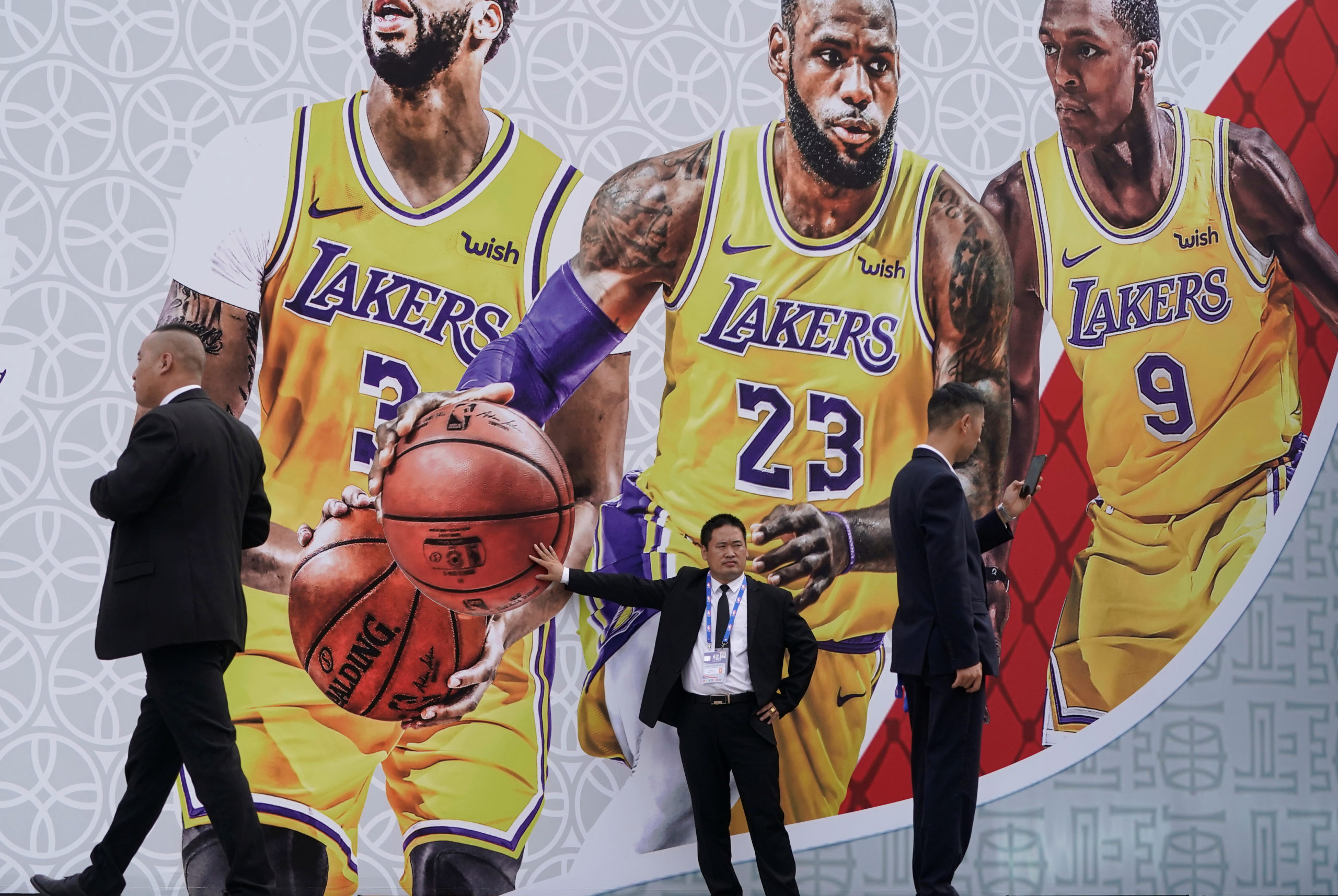 Le personnel de sécurité se tient devant un panneau d'affichage avec une image des joueurs de basket-ball des Lakers de Los Angeles devant le lieu prévu pour des événements de fans avant un match NBA Chine entre les Brooklyn Nets et les Los Angeles Lakers au Oriental Sports Center à Shanghai, Chine 9. Octobre 2019.