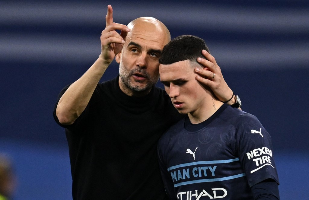 Manchester City's Spanish manager Pep Guardiola (L) hungs Manchester City's English midfielder Phil Foden after the UEFA Champions League semi-final second leg football match between Real Madrid CF and Manchester City at the Santiago Bernabeu stadium in Madrid on May 4, 2022. -