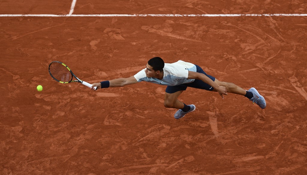 Spain's Carlos Alcaraz stretches to return the ball to Spain's Albert Ramos-Vinolas during their men's singles match on day four of the Roland-Garros Open tennis tournament at the Court Simonne-Mathieu in Paris on May 25, 2022. (Photo by Christophe ARCHAMBAULT / AFP)