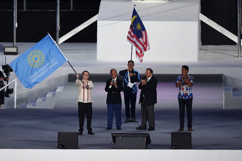 Philippines Foreign minister Alan Peter Cayetano (L) waves the Southeast Asian Games flag following the handover ceremony as next SEA Games hosts, during the closing ceremony of the 29th Southeast Asian Games (SEA Games) at Bukit Jalil stadium in Kuala Lumpur on August 30, 2017.