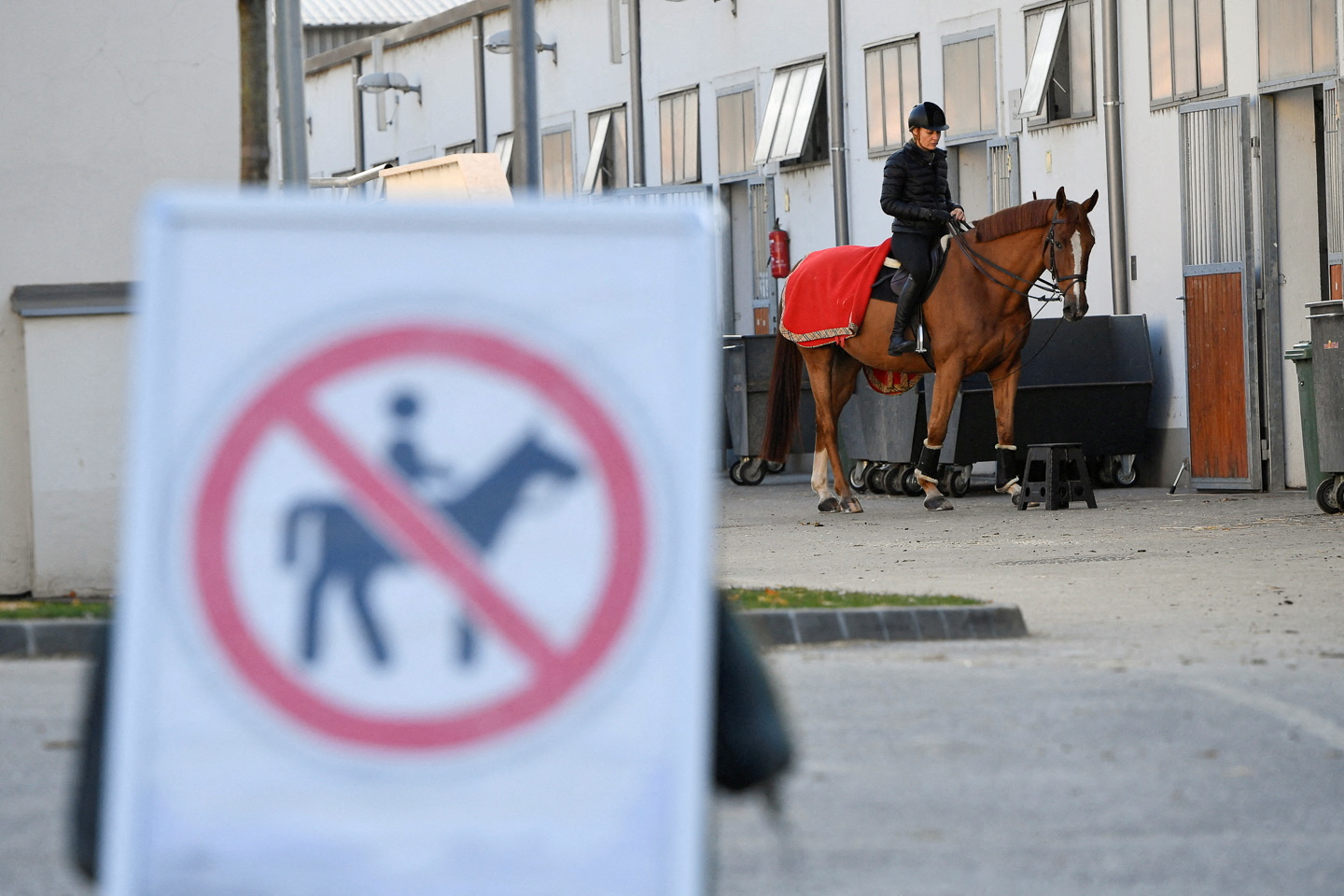 FILE PHOTO: A rider with her horse are seen next to a no riding zone sign during a news conference about keeping horse riding in the modern pentathlon program in Budapest, Hungary, November 12, 2021. 