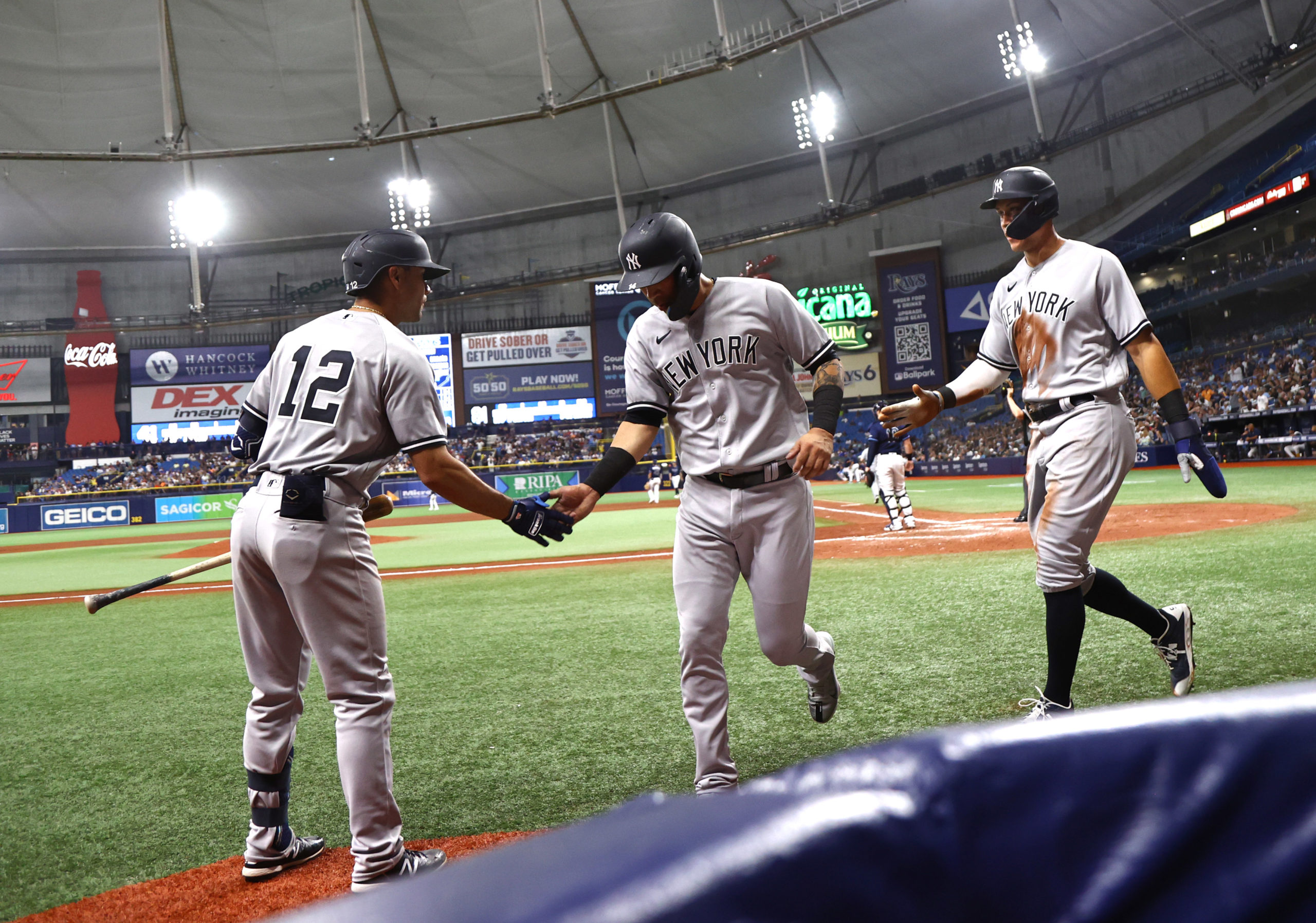 May 26, 2022; St. Petersburg, Florida, USA;  New York Yankees third baseman Marwin Gonzalez (14) and right fielder Aaron Judge (99) are congratulated by shortstop Isiah Kiner-Falefa (12) after scoring during the sixth inning against the Tampa Bay Rays at Tropicana Field. Mandatory Credit: Kim Klement-USA TODAY Sports