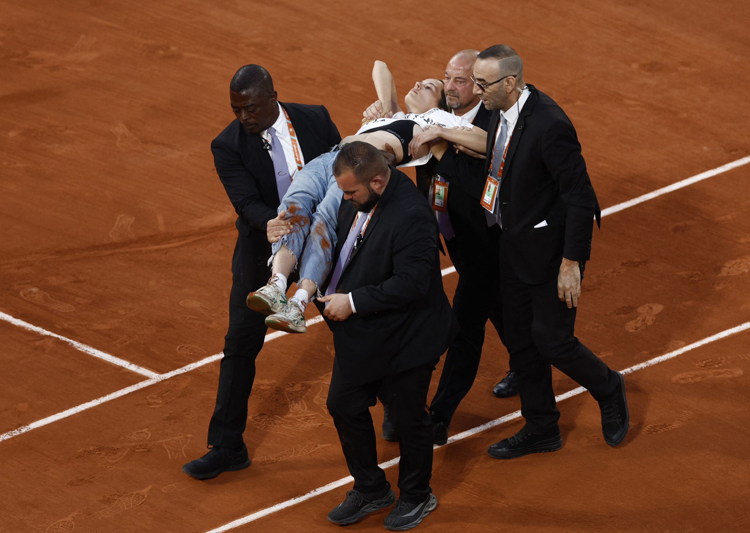 Tenis - Prancis Terbuka - Roland Garros, Paris, Prancis - 3 Juni 2022 Anggota keamanan turun dari lapangan seorang pengunjuk rasa setelah dia mengikat dirinya ke net selama semi final antara Casper Ruud dari Norwegia dan Marin Cilic dari Kroasia REUTERS/Yves Herman