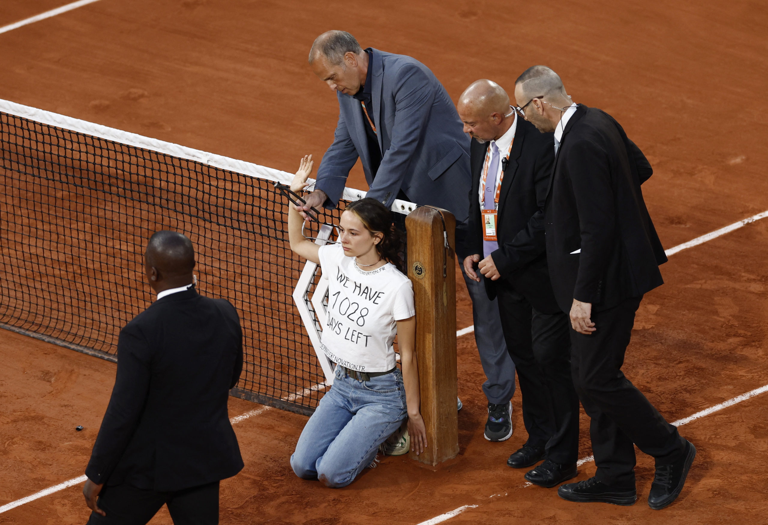 Tennis - French Open - Roland Garros, Paris, France - June 3, 2022 Protestor ties herself to the net during the semi final between Norway's Casper Ruud and Croatia's Marin Cilic as security members cut the ties REUTERS/Yves Herman