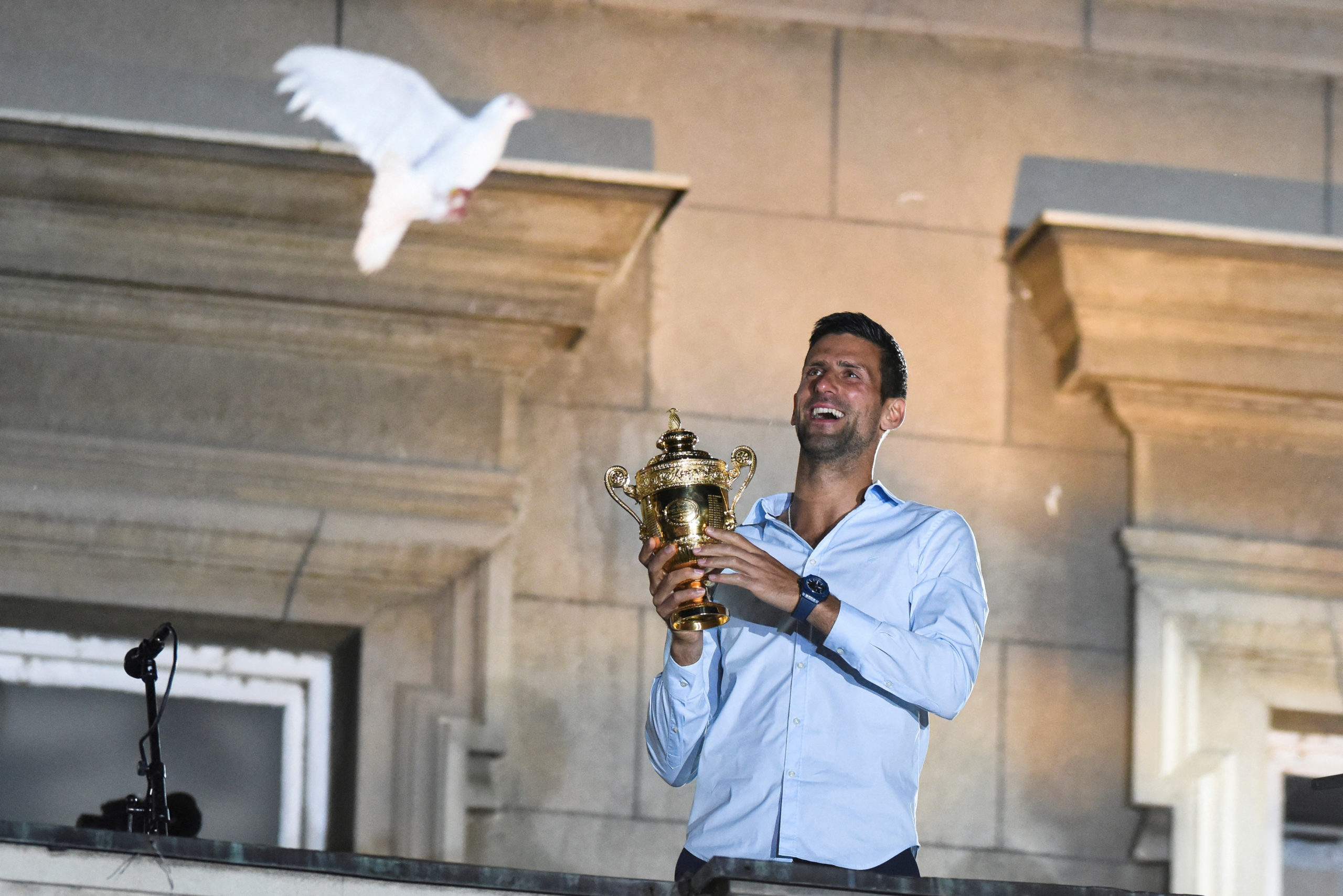 Serbian tennis player Novak Djokovic holds up the winner's trophy and greets fans during a welcoming ceremony in front of the city hall in Belgrade, in Serbia