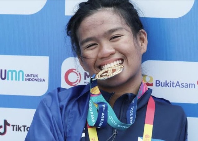 Rookie Angel Otom takes a bite at her gold medal after winning the women’s 50-meter butterfly S5 event on the way to emerging as the country’s first triple gold medalist in the 11th ASEAN Para Games at the Jatadiri Sports Complex pool in Semarang, Indonesia. 