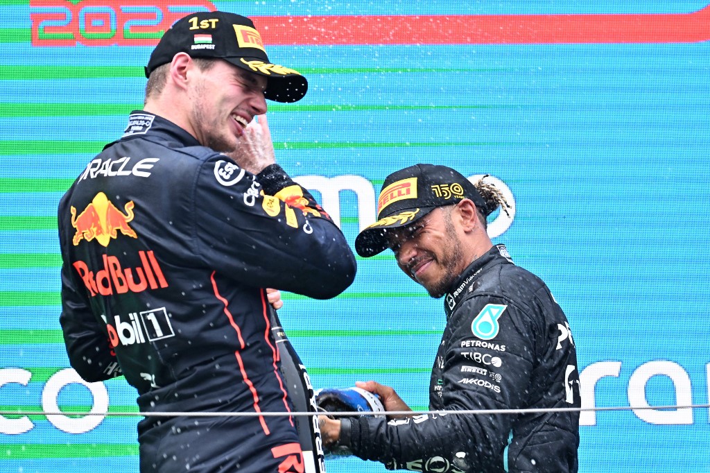 Second placed Mercedes' British driver Lewis Hamilton (R) and winner Red Bull Racing's Dutch driver Max Verstappen celebrate on the podium with champagne after the Formula One Hungarian Grand Prix at the Hungaroring in Mogyorod near Budapest, Hungary, on July 31, 2022.