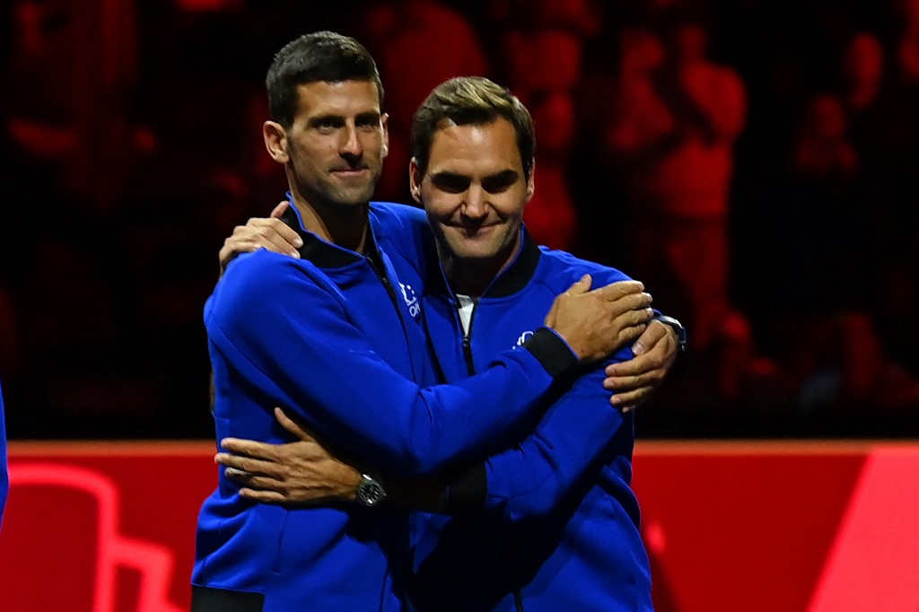 Serbia's Novak Djokovic (L) embraces Switzerland's Roger Federer (R) at the presentation ceremony as Team World players celebrate victory over Team Europe in the 2022 Laver Cup at the O2 Arena in London on September 25, 2022.