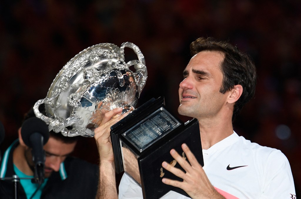 Switzerland's Roger Federer cries as he holds the winner's trophy after beating Croatia's Marin Cilic (L) in their men's singles final match on day 14 of the Australian Open tennis tournament in Melbourne on January 28, 2018.