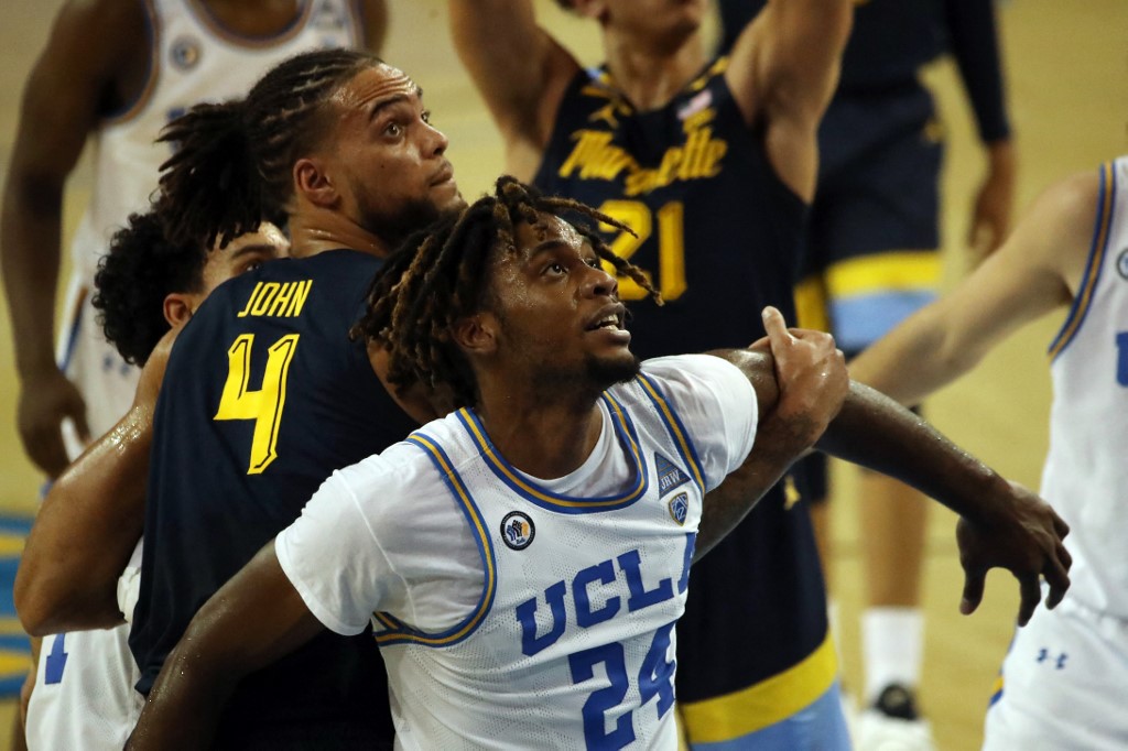  Jalen Hill #24 of the UCLA Bruins and Theo John #4 of the Marquette Golden Eagles fight for the rebound during the second half at UCLA Pauley Pavilion on December 11, 2020 in Los Angeles, California.   