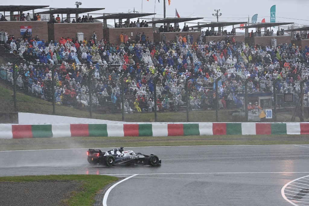 AlphaTauri's French driver Pierre Gasly travels past fans during a rainstorm at the Formula One Japanese Grand Prix at Suzuka, Mie prefecture on October 9, 2022. 