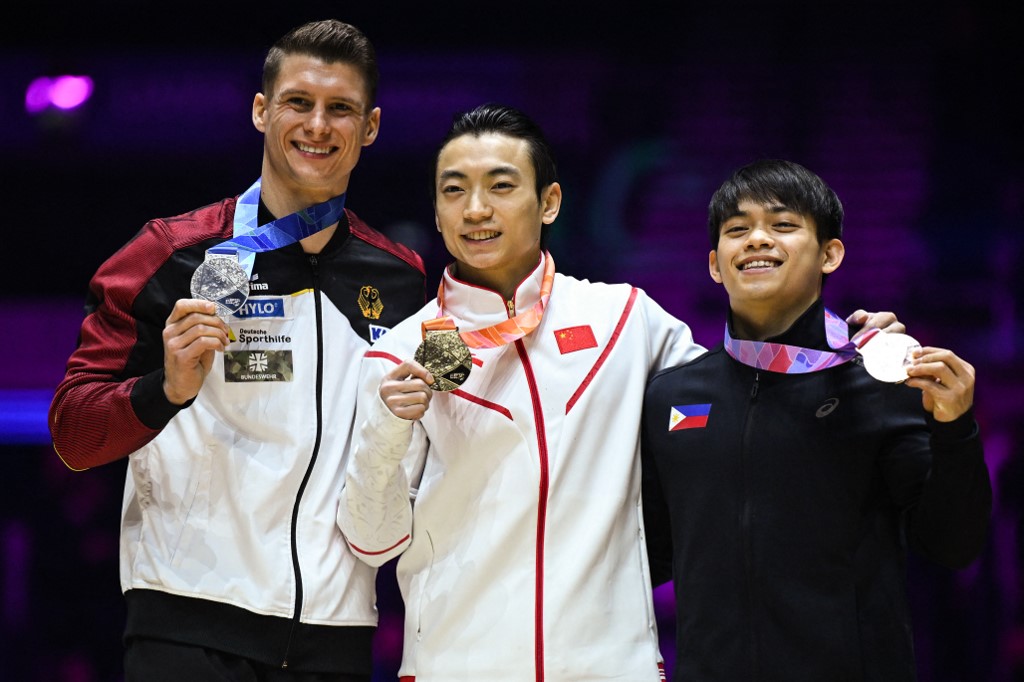 (From L) Second-placed Germany's Lukas Dauser, first-placed China's Zou Jingyuan and third-placed Philippines' Carlos Edriel Yulo celebrate on the podium after competing in the Men's Parallel Bars final at the World Gymnastics Championships in Liverpool, northern England on November 6, 2022.