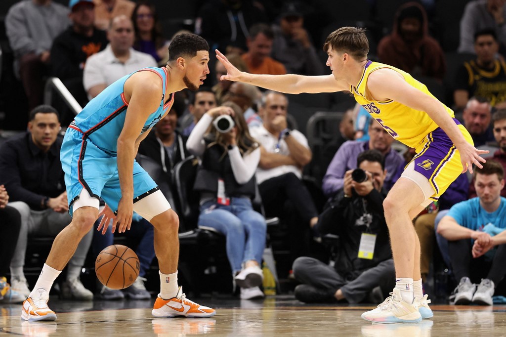 Devin Booker #1 of the Phoenix Suns tackles the ball against Austin Reaves #15 of the Los Angeles Lakers during the second half of an NBA game at Footprint Center on November 22, 2022 in Phoenix, Arizona.
