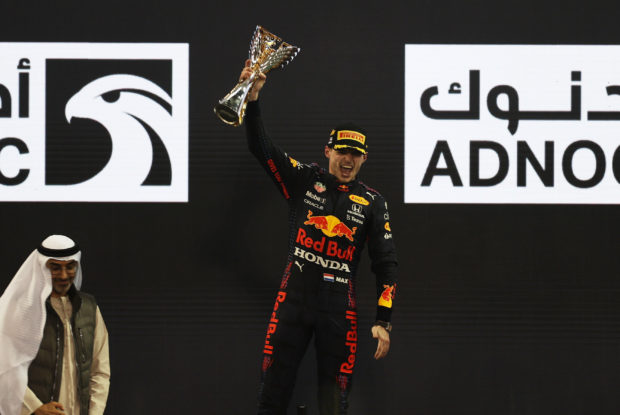 FILE PHOTO: Formula One F1 - Abu Dhabi Grand Prix - Yas Marina Circuit, Abu Dhabi, United Arab Emirates - December 12, 2021 Red Bull's Max Verstappen celebrates winning the race and the world championship with the trophy on the podium REUTERS/Rula 