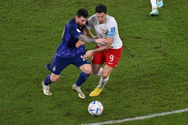 Poland's No. 09 striker Robert Lewandowski (right) and Argentina's No. 10 striker Lionel Messi compete for the ball during the 2022 World Cup Group C soccer match between Poland and Argentina at the 974 Stadium in Doha on November 30 2022. (Photo by Glyn KIRK/AFP)