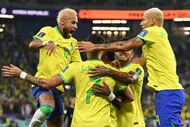 O atacante brasileiro # 20 Vinicius Junior (C) comemora com seus companheiros após marcar o primeiro gol de sua equipe durante a partida de futebol das oitavas de final da Copa do Mundo Qatar 2022 entre Brasil e Coreia do Sul no Estádio 974 em Doha em 5 de dezembro de 2022 (Foto de Manan) FATCIANA/AFP )