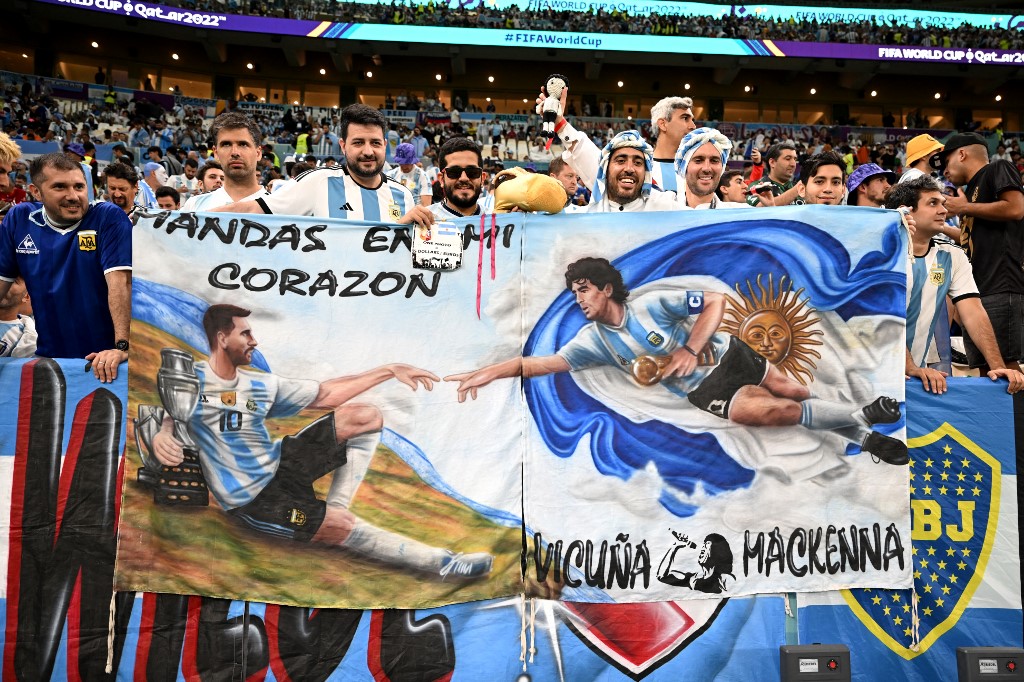 Argentina supporters display a banner depicting an image of Argentina's No 10 striker Lionel Messi and late Argentina soccer star Diego Maradona before the start of the 2022 World Cup quarter-final soccer match between the Netherlands and Argentina at Lusail Stadium, north of Doha on December 9, 2022. 