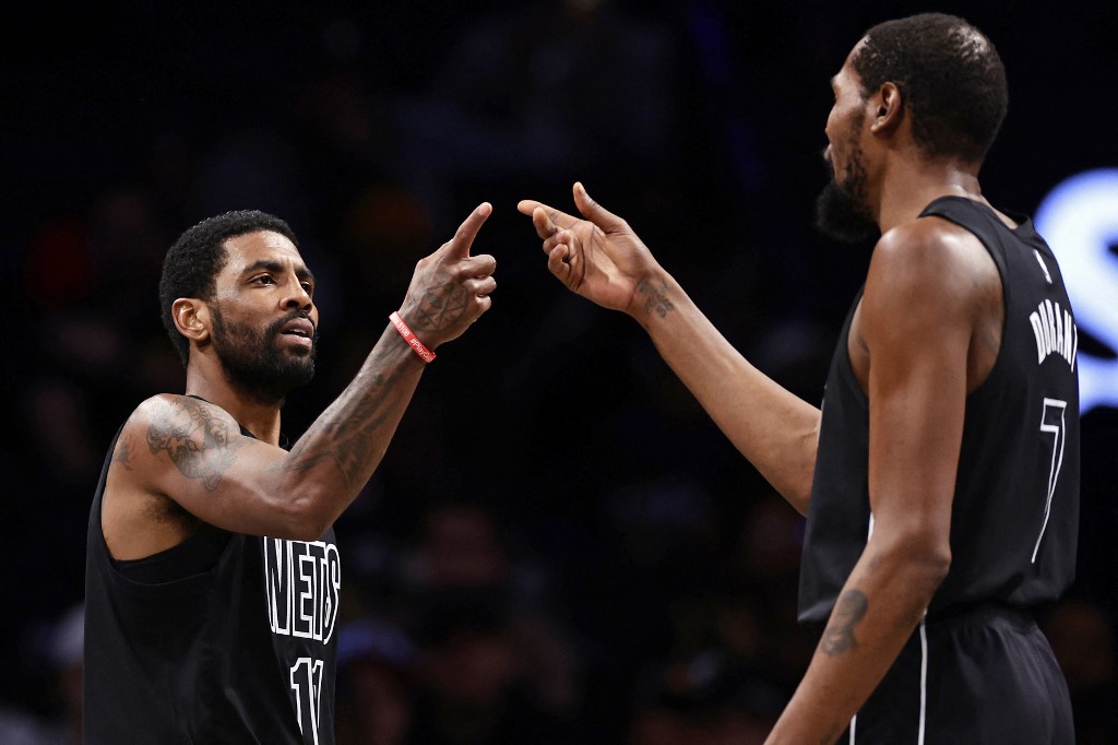 Kyrie Irving #11 of the Brooklyn Nets reacts with teammate Kevin Durant #7 against the Toronto Raptors during the second half at Barclays Center on December 2, 2022 in New York City.
