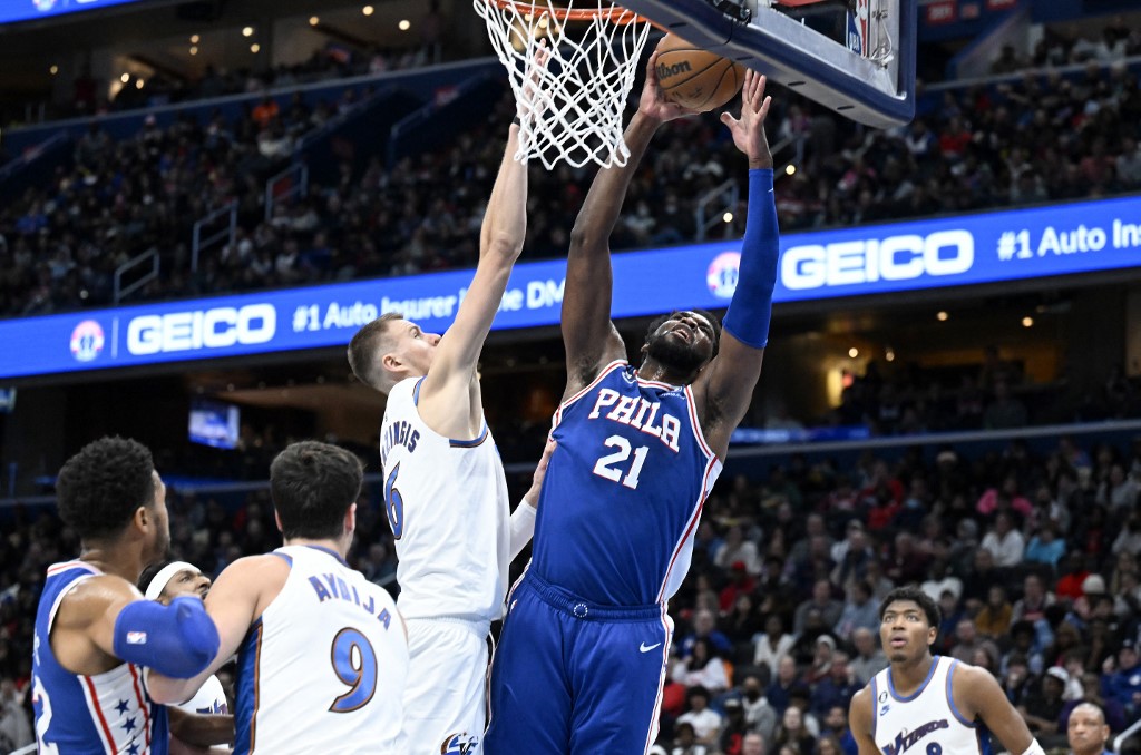 Joel Embiid #21 of the Philadelphia 76ers drives to the basket in the second quarter against Kristaps Porzingis #6 of the Washington Wizards at Capital One Arena on December 27, 2022 in Washington, DC. 
