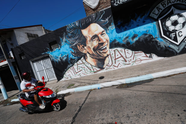 Un hombre conduce una motocicleta frente a un mural que representa a la estrella del fútbol argentino Lionel Messi a pocas cuadras de la casa donde nació, en Rosario, Argentina, el 15 de diciembre de 2022. REUTERS/Agustin Marcarian