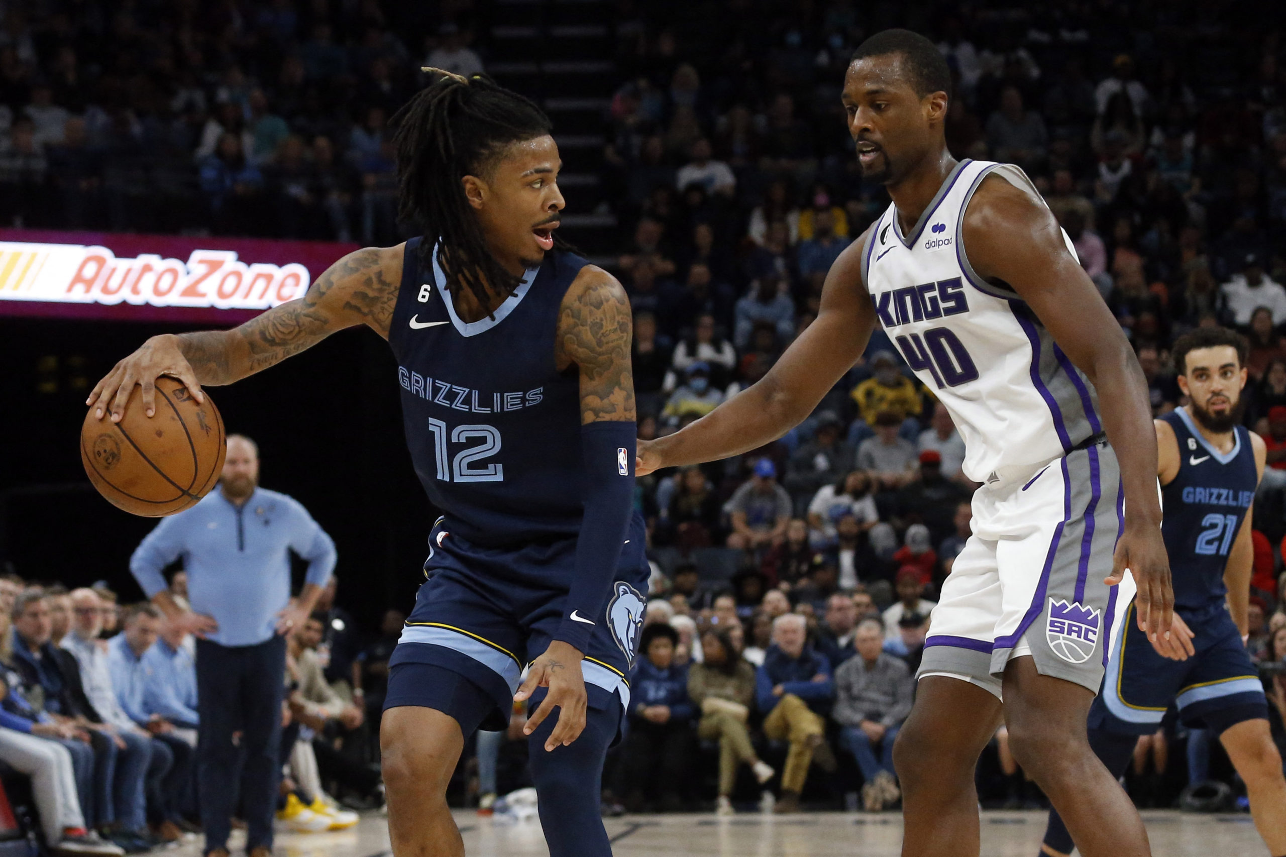 Jan 1, 2023; Memphis, Tennessee, USA; Memphis Grizzlies guard Ja Morant (12) passes the ball behind his back as Sacramento Kings forward Harrison Barnes (40) defends during the second half at FedExForum. 