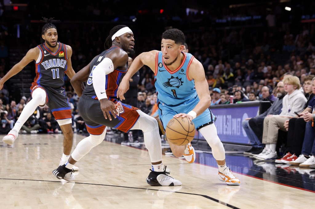 Devin Booker #1 of the Phoenix Suns drives past Luguentz Dort #5 of the Oklahoma City Thunder during the second half at Footprint Center on February 24, 2023 in Phoenix, Arizona