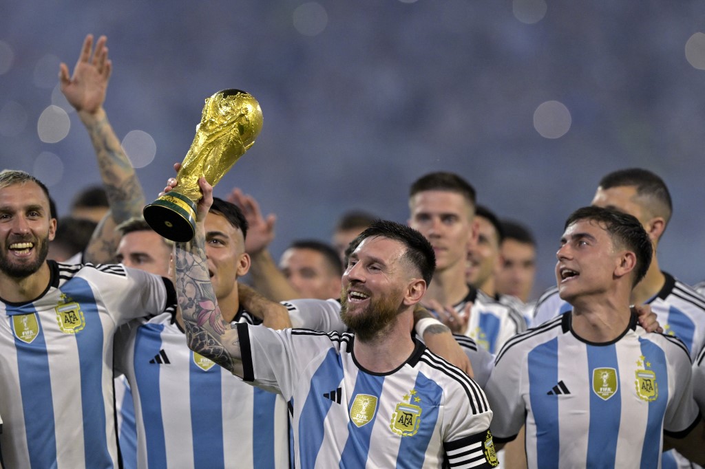 Argentina's forward Lionel Messi (C) raises a replica of the World Cup trophy next to his teammates during a recognition ceremony for the World Cup-winning players, following the friendly football match between Argentina and Curacao at the Madre de Ciudades stadium in Santiago del Estero, in northern Argentina, on March 28, 2023. (Photo by JUAN MABROMATA / AFP)