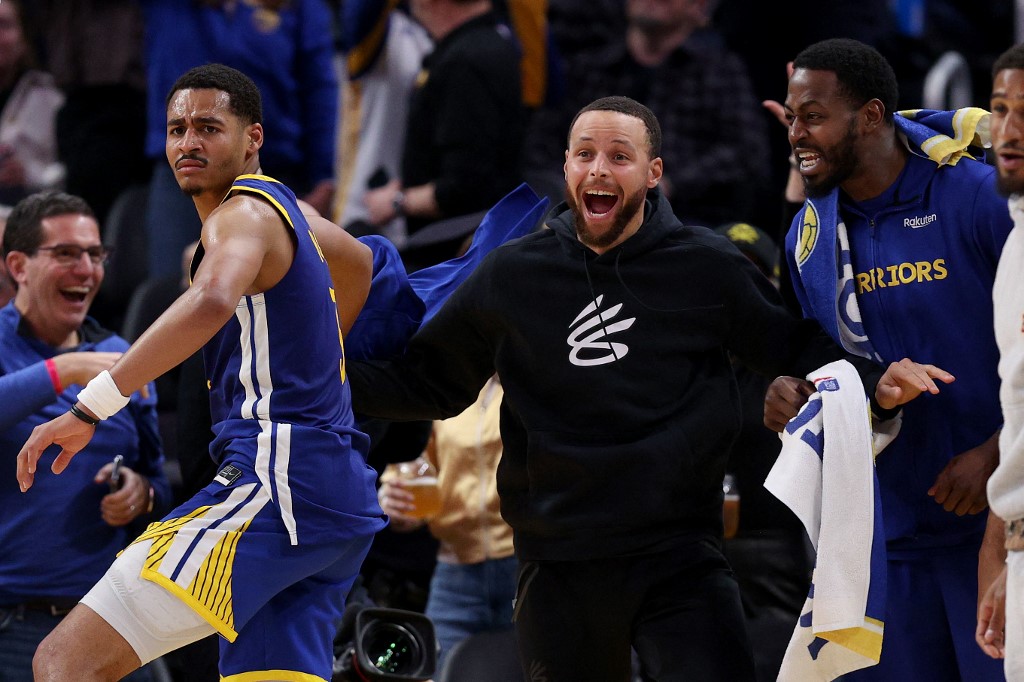 Injured Stephen Curry #30 of the Golden State Warriors celebrates with teammates after Jonathan Kuminga #00 of the Golden State Warriors dunked the ball against the Portland Trail Blazers at Chase Center on February 28, 2023 in San Francisco, 