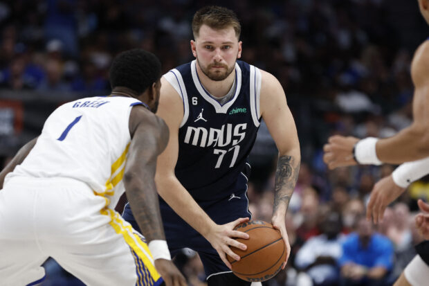 In this file photo taken on March 22, 2023, Luka Doncic of the Dallas Mavericks looks to pass while defended by JaMychal Green of the Golden State Warriors in the second half at American Airlines Center . NOTE TO USER: User expressly acknowledges and agrees that, by downloading and or using this photograph, User is consenting to the terms and conditions of the Getty Images License Agreement. Tim Heitman/Getty Images/AFP - Doncic was fined $35,000 by the NBA on March 24, 2023, for making a gesture implying a payoff to a referee for a non-call against Golden State's Draymond Green. (Photo by Tim Heitman / GETTY IMAGES NORTH AMERICA / AFP)