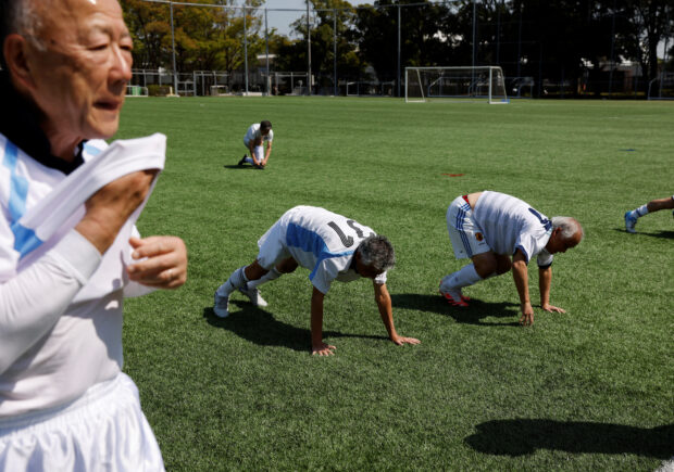 FILE PHOTO: Nihon Soccer OB Club members, a team whose members’ average age is 77.4-year-old, do physical training before a practice match in Tokyo, Japan, April 4, 2023. 