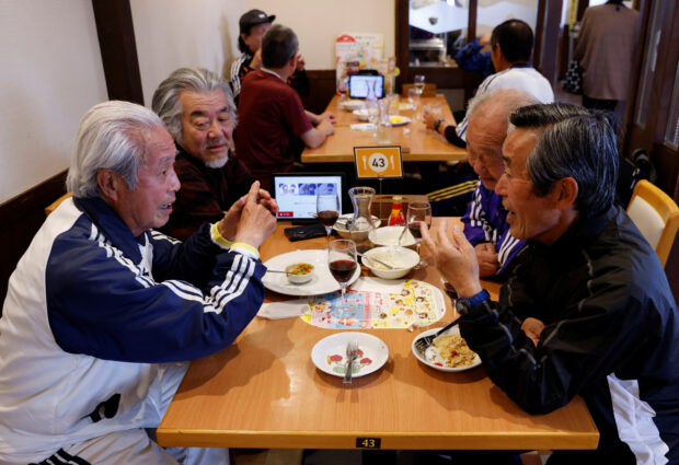 FILE PHOTO: Mutsuhiko Nomura (1st to the left), 83, chats with his TAFF (Tama Area Friday Football) teammates, a football team where the players’ average age is 65-year-old, at a restaurant after their practice in Tokyo, Japan, March 31, 2023.