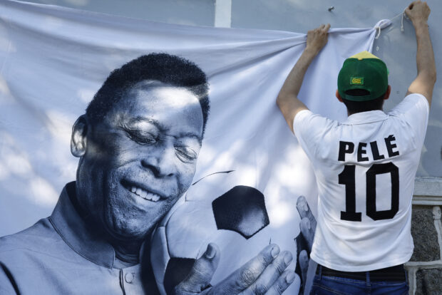 Vista general de un aficionado con la camiseta de Pelé y colocando una pancarta con la imagen de Pelé.  REUTERS/Amanda Perobelli