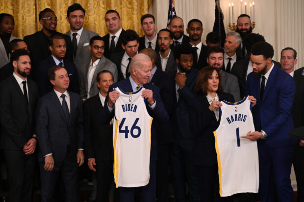 US President Joe Biden and US Vice President Kamala Harris are presented with jerseys from members of the Golden State Warriors basketball team during a celebration for their 2022 NBA championship, in the East Room of the White House in Washington, DC, on January 17, 2023. (Photo by Andrew CABALLERO-REYNOLDS / AFP)