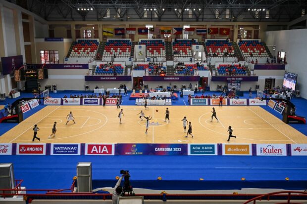 منظر عام يظهر لاعبين من تايلاند (باللون الأبيض) وماليزيا (باللون الأسود) يتنافسون في مباراة دور المجموعات في كرة السلة للسيدات في ألعاب SEA (ألعاب جنوب شرق آسيا) في بنوم بنه في 13 مايو 2023.